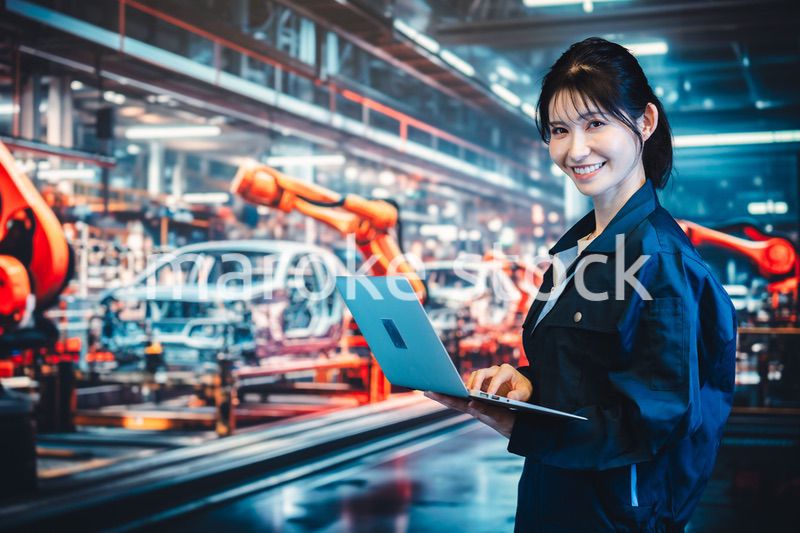 工場の生産ラインでパソコンを使う若い女性