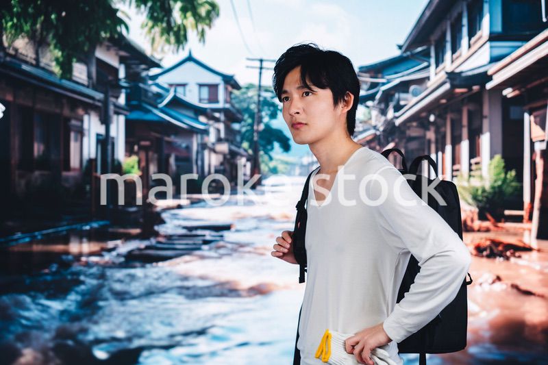 大雨で浸水した街から避難する男性