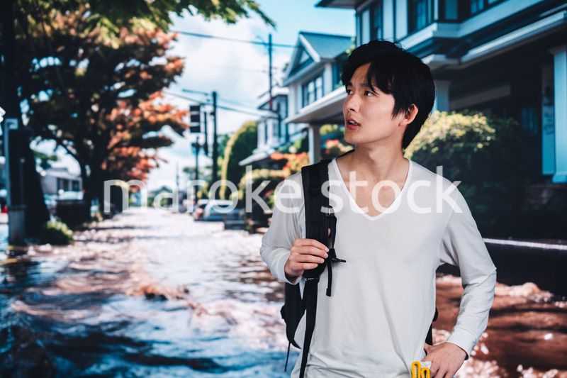 大雨で浸水した街から避難する男性