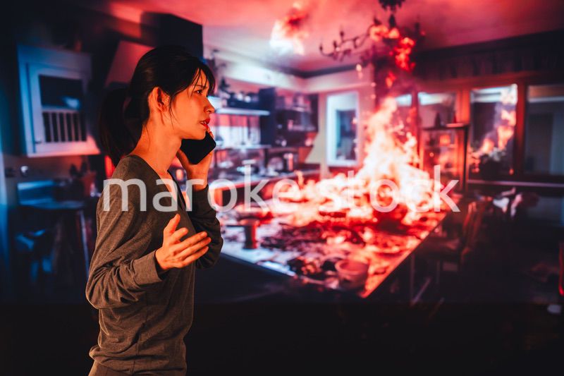 火災が発生し消防に通報をする若い女性