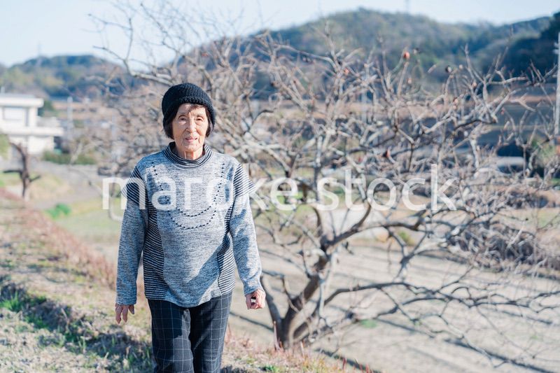 田舎の道を散歩する高齢の女性