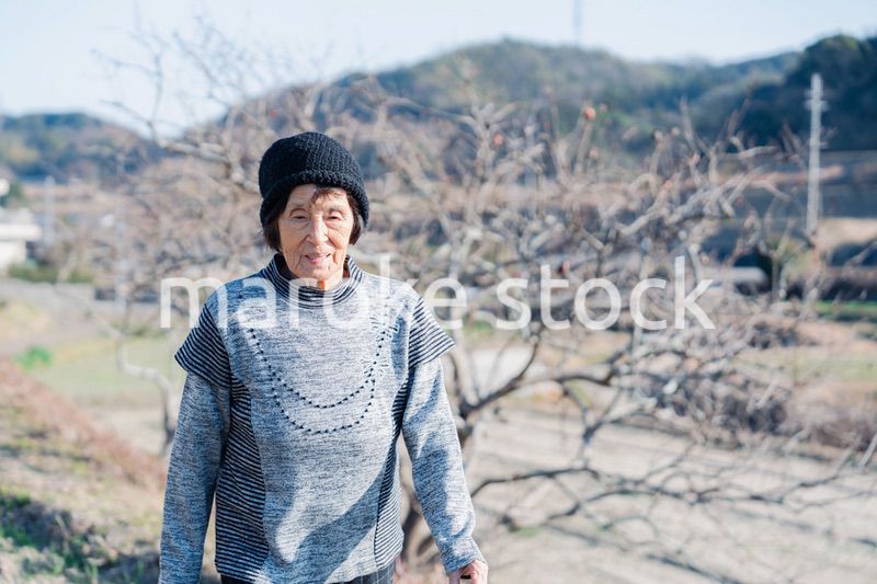 田舎の道を散歩する高齢の女性