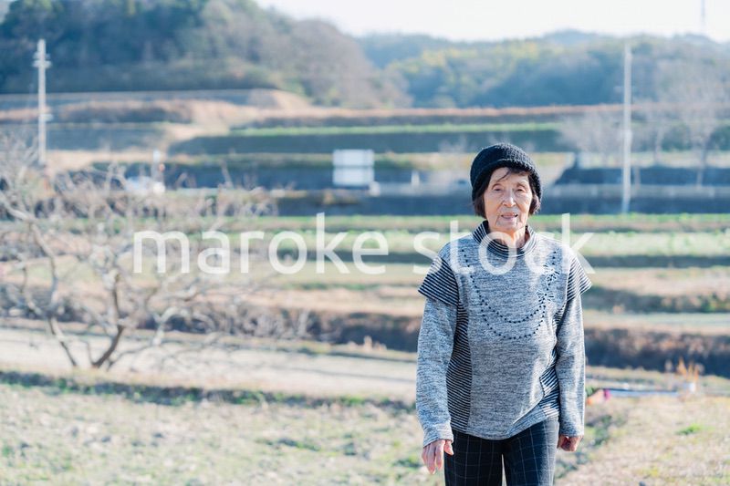田舎の道を散歩する高齢の女性