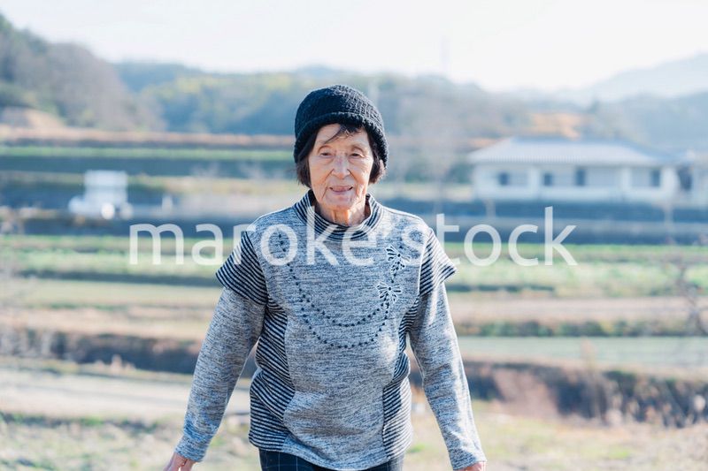 田舎の道を散歩する高齢の女性