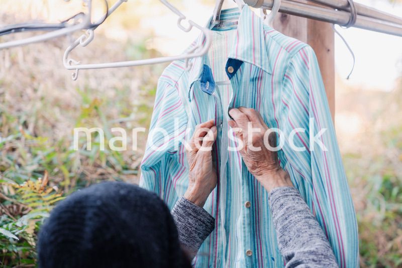 外に洗濯物を干す高齢の女性