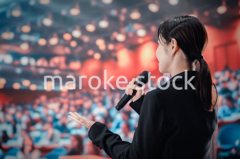 大勢の聴衆の前でスピーチをする女性