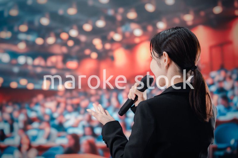 大勢の聴衆の前でスピーチをする女性