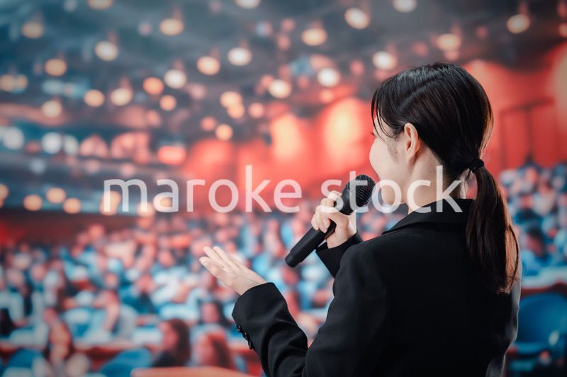 大勢の聴衆の前でスピーチをする女性