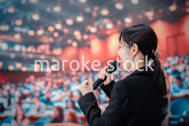大勢の聴衆の前でスピーチをする女性