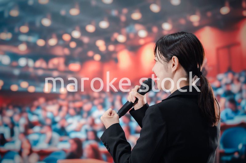 大勢の聴衆の前でスピーチをする女性