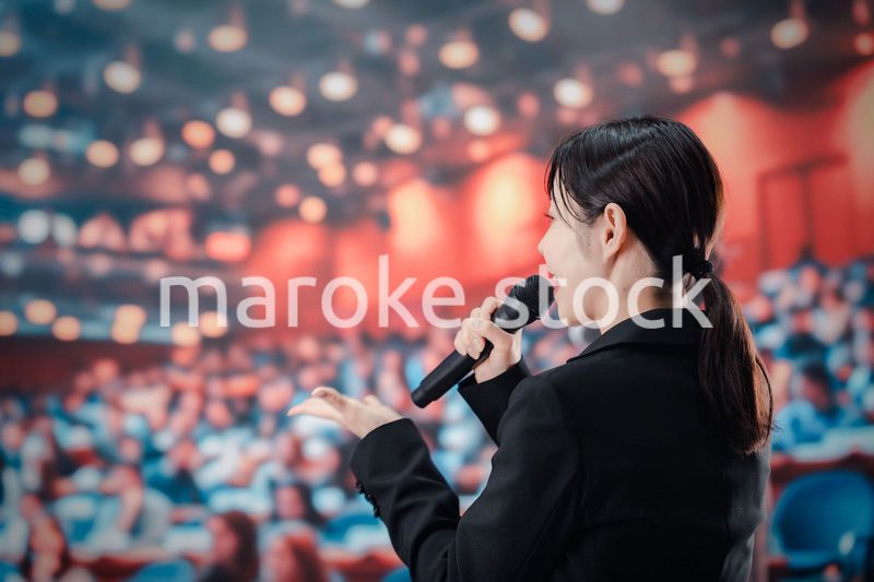 大勢の聴衆の前でスピーチをする女性