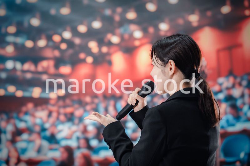 大勢の聴衆の前でスピーチをする女性