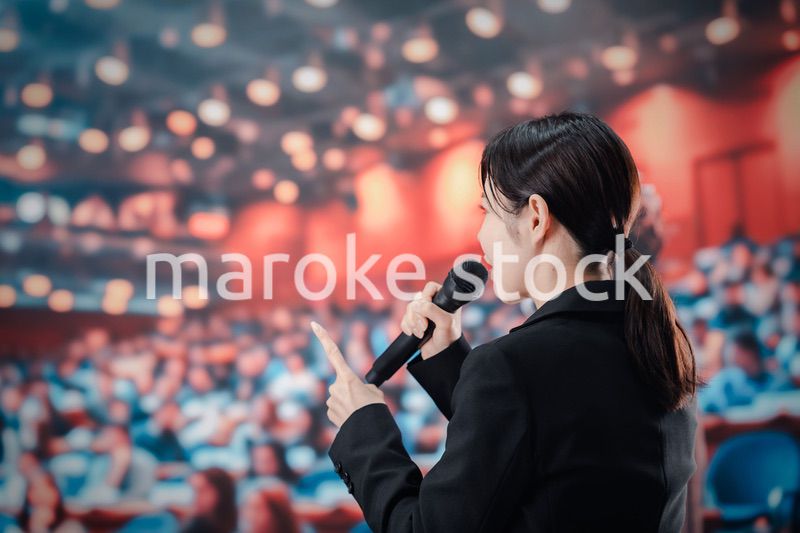 大勢の聴衆の前でスピーチをする女性