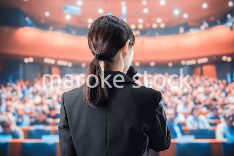 大勢の前でマイクで話す女性