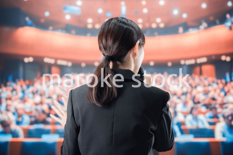 大勢の前でマイクで話す女性