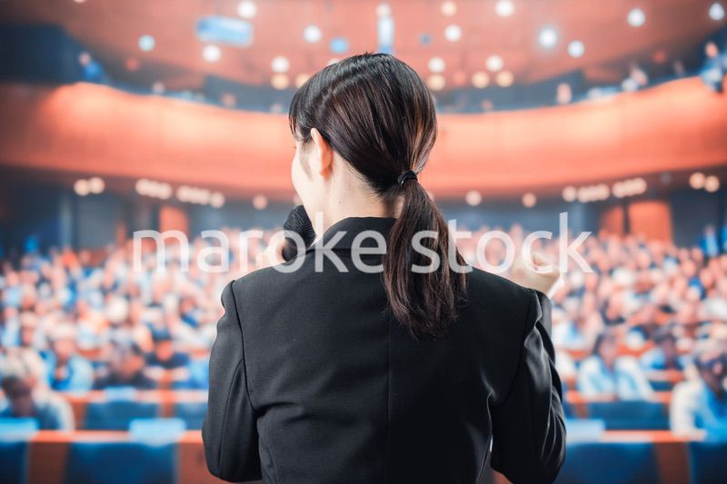 大勢の前でマイクで話す女性