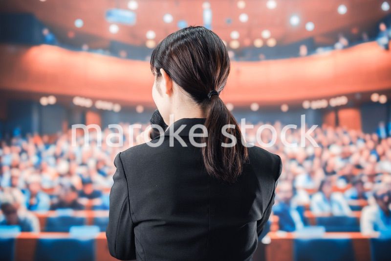 大勢の前でマイクで話す女性