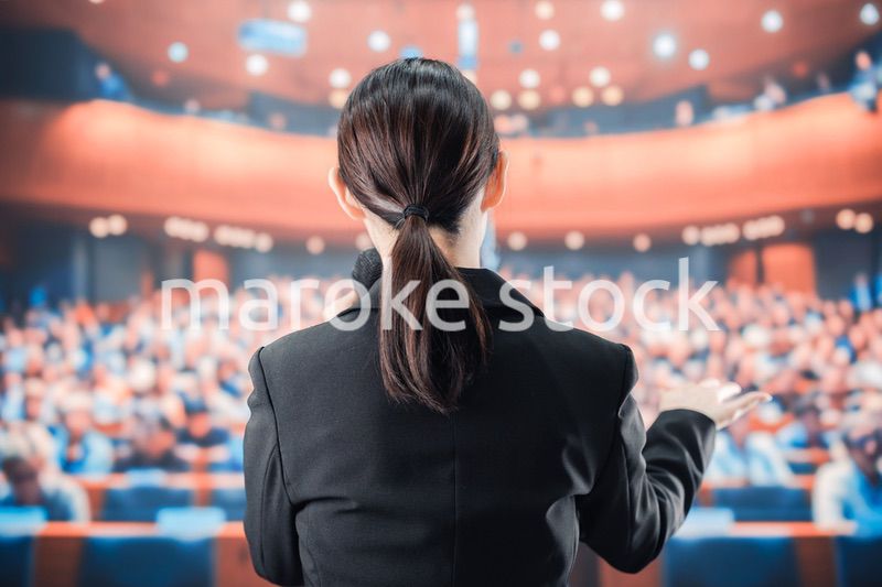 大勢の前でマイクで話す女性