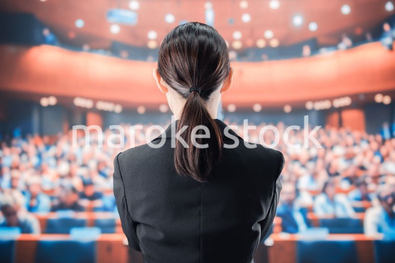 大勢の前でマイクで話す女性
