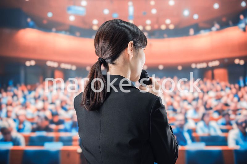 大勢の前でマイクで話す女性