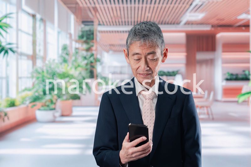 笑顔でスマホを使う中年のビジネスマン