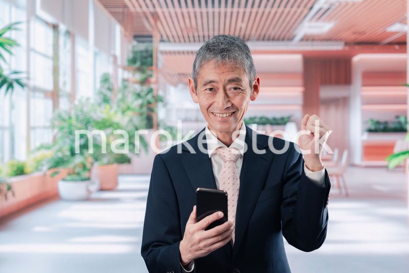 笑顔でスマホを使う中年のビジネスマン