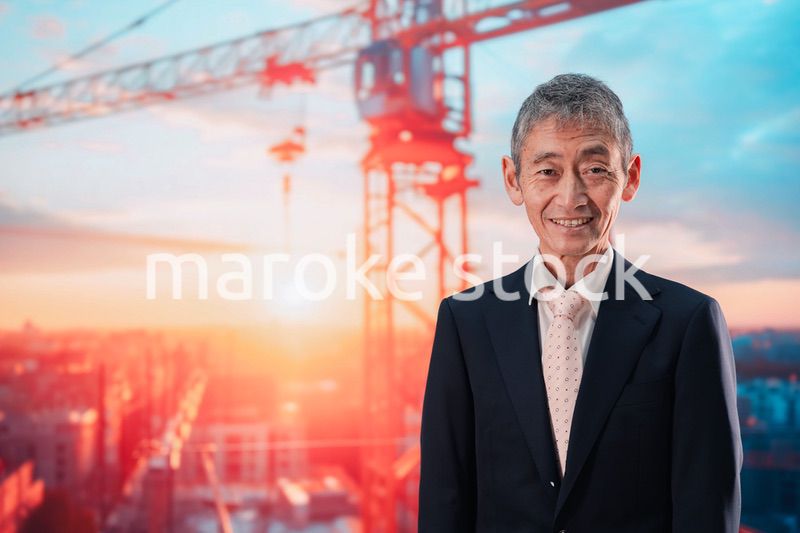 タワークレーンの前に立つスーツ姿の男性ビジネスマン