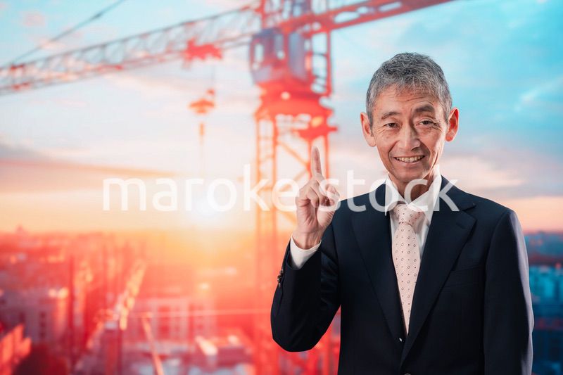 タワークレーンの前に立つスーツ姿の男性ビジネスマン