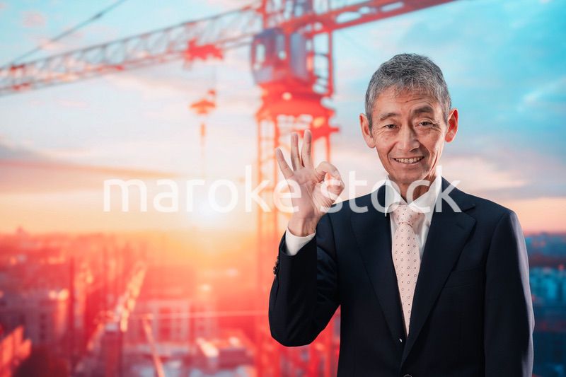 タワークレーンの前に立つスーツ姿の男性ビジネスマン