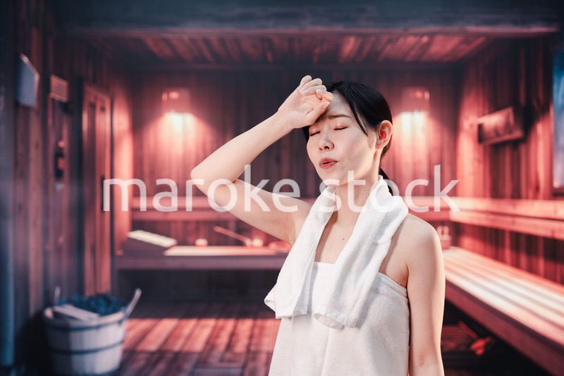 サウナで汗をかく若い女性