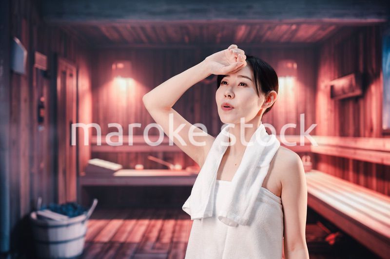 サウナで汗をかく若い女性