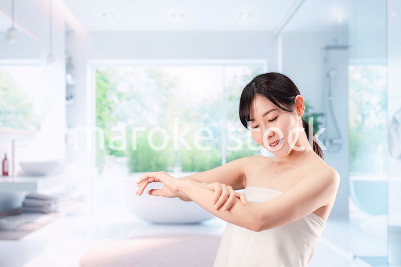 バスルームでボディケアをする若い女性