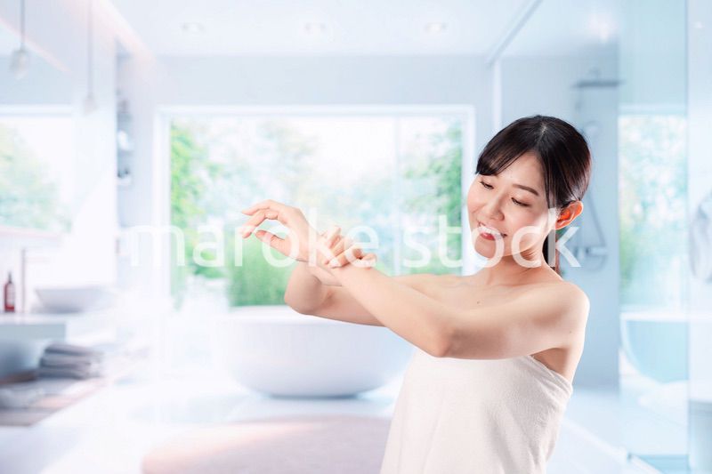 バスルームでボディケアをする若い女性