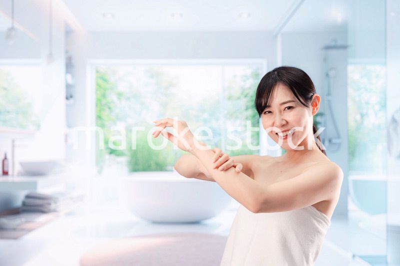 バスルームでボディケアをする若い女性