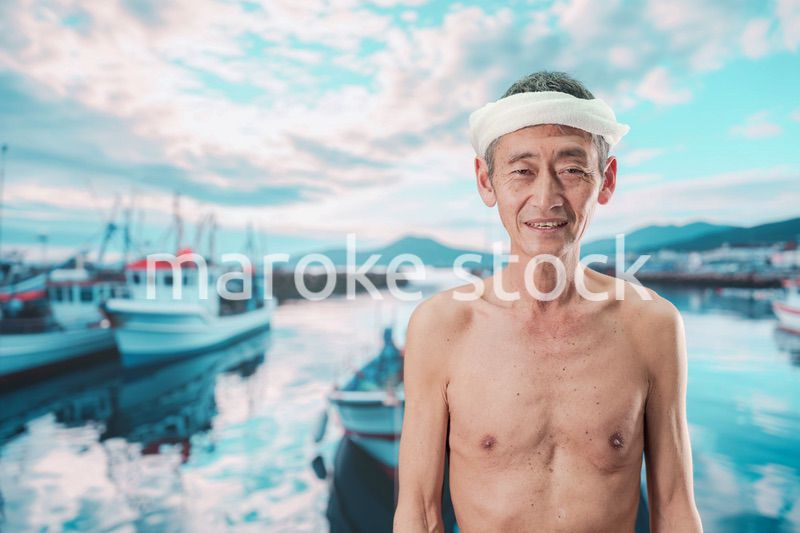 笑顔で腕を組む高齢の漁師