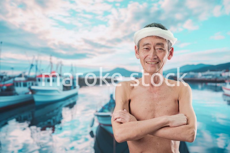 笑顔で腕を組む高齢の漁師