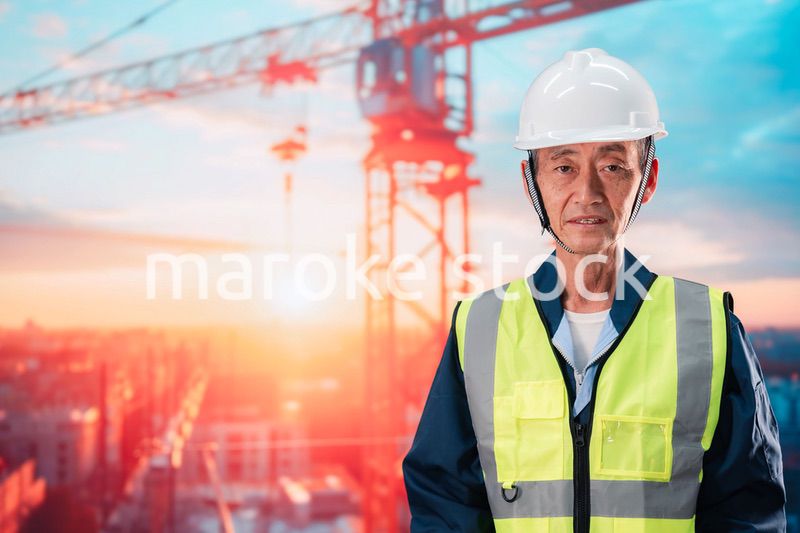 高層ビルの建設現場で監督をする高齢の男性