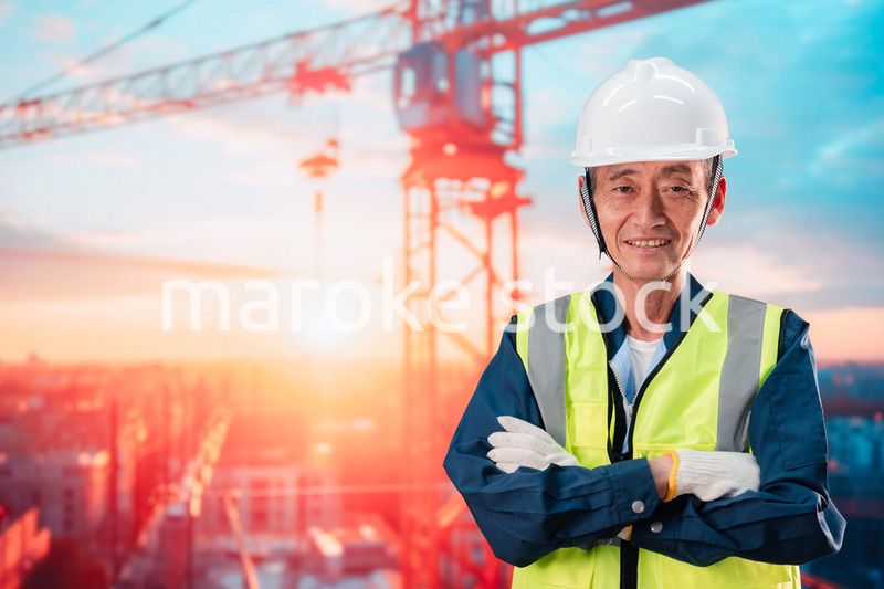 高層ビルの建設現場で監督をする高齢の男性