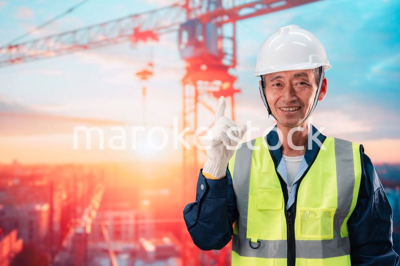 高層ビルの建設現場で監督をする高齢の男性