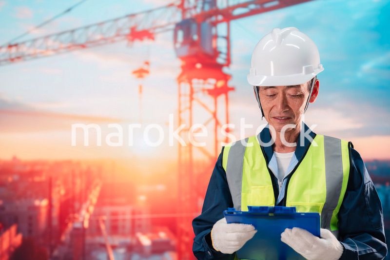 高層ビルの建設現場で監督をする高齢の男性