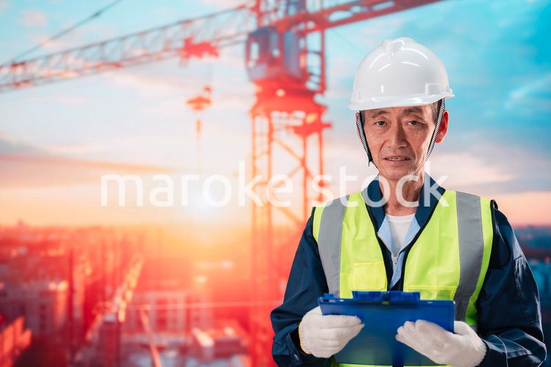 高層ビルの建設現場で監督をする高齢の男性