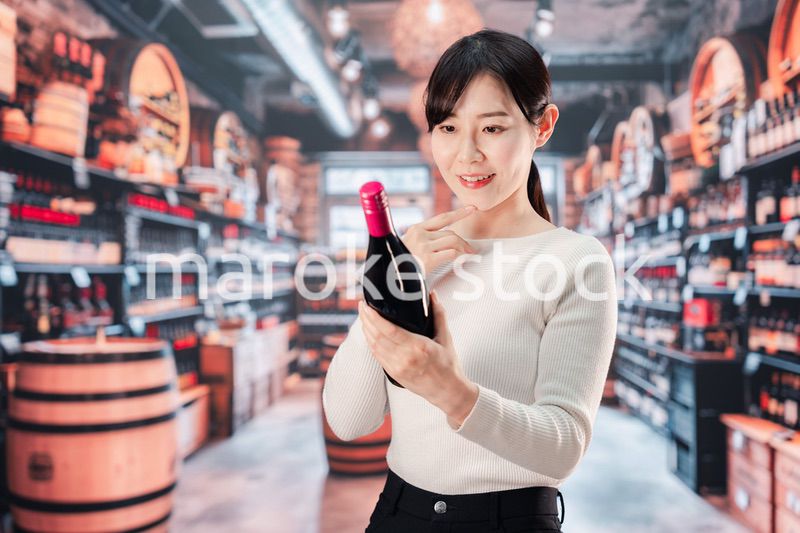 ワインショップでワインを選ぶ若い女性