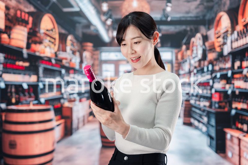 ワインショップでワインを選ぶ若い女性