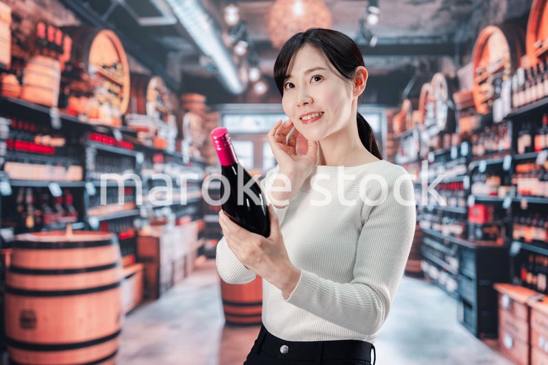 ワインショップでワインを選ぶ若い女性
