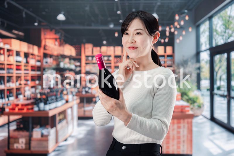 ワインショップでワインを選ぶ若い女性