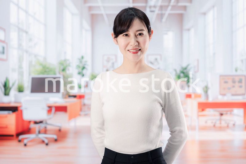 ビジネスカジュアルでオフィスに立つ若い女性