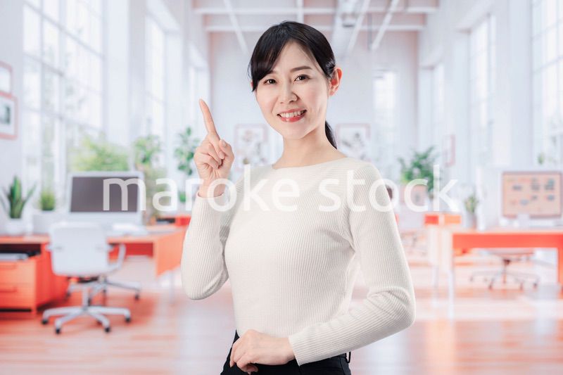 ビジネスカジュアルでオフィスに立つ若い女性