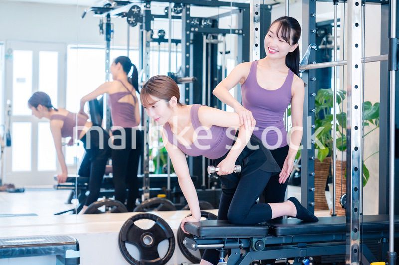 ジムで女性コーチのパーソナルトレーニングを受ける女性