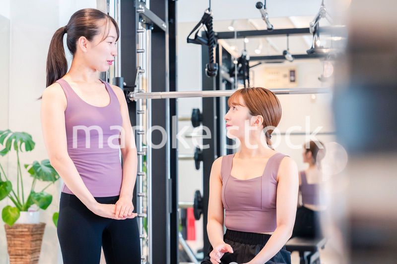 ジムで女性コーチのパーソナルトレーニングを受ける女性