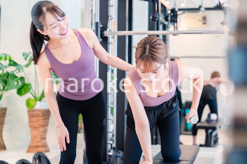 ジムで女性コーチのパーソナルトレーニングを受ける女性